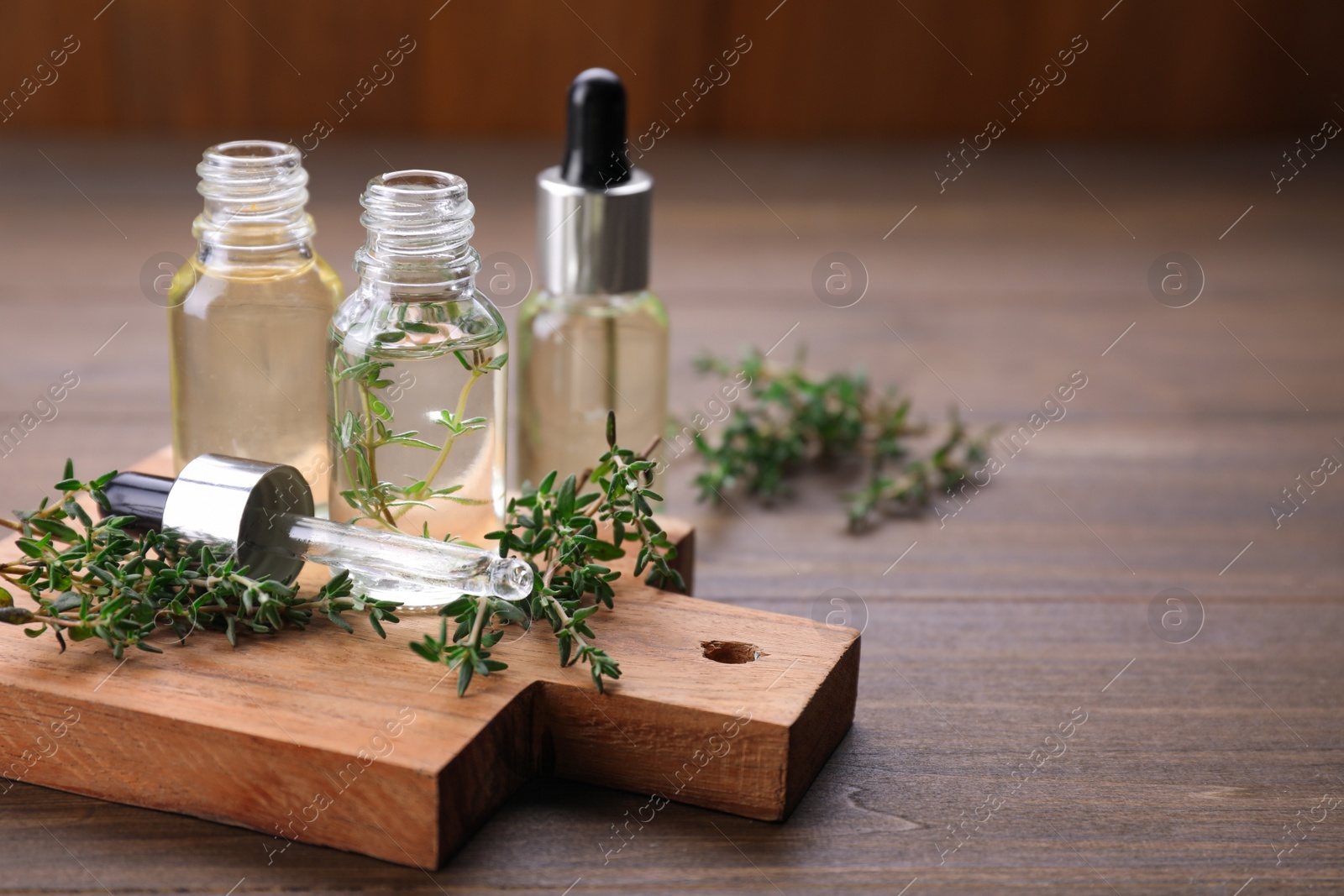 Photo of Thyme essential oil on wooden table, space for text