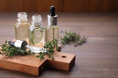 Thyme essential oil on wooden table, space for text