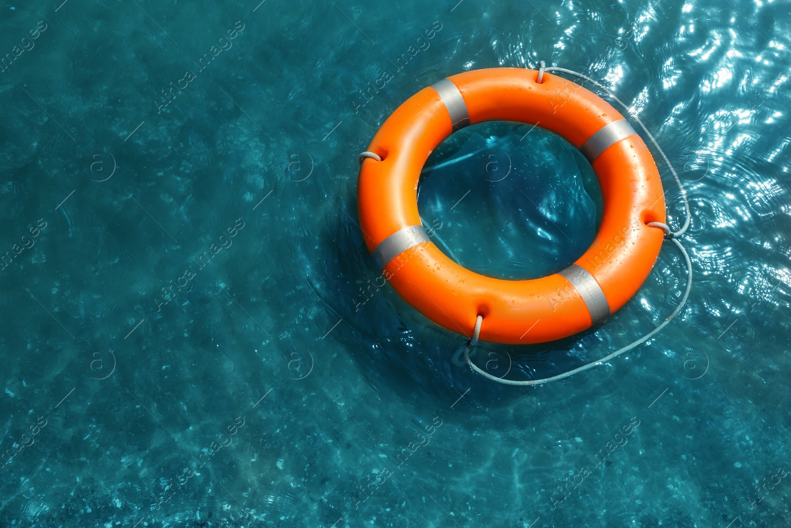 Photo of Orange life buoy floating in sea, above view. Emergency rescue equipment