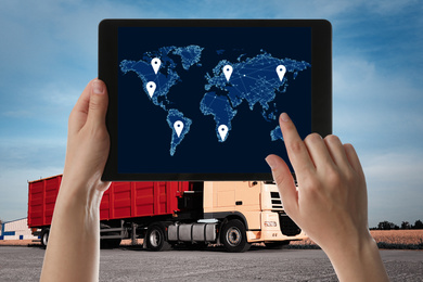 Image of Logistics concept. Woman using tablet with world map on screen against truck