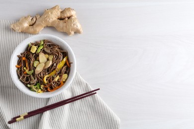 Photo of Stir-fry. Delicious cooked noodles with chicken and vegetables in bowl served on light wooden table, flat lay. Space for text