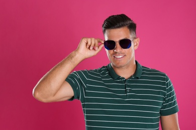 Handsome man wearing sunglasses on pink background