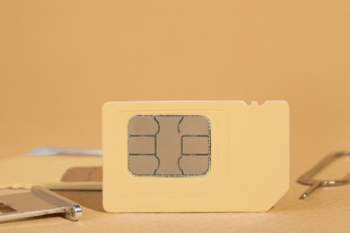 Different SIM cards, tray and ejector on beige background, closeup