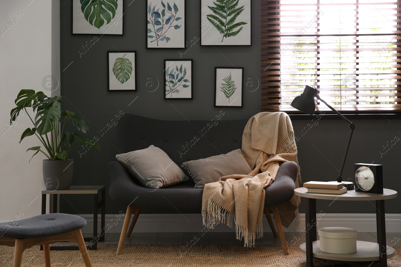 Photo of Beautiful artworks and comfortable sofa in stylish room. Interior design