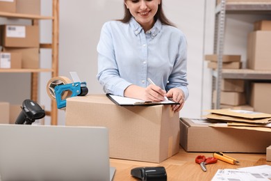 Parcel packing. Post office worker with clipboard writing notes at wooden table indoors