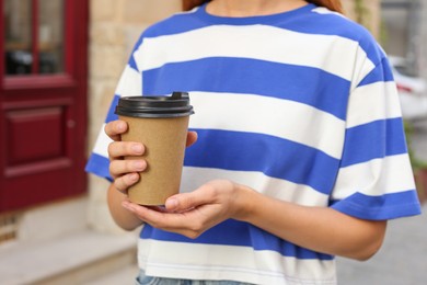 Coffee to go. Woman with paper cup of drink outdoors, closeup