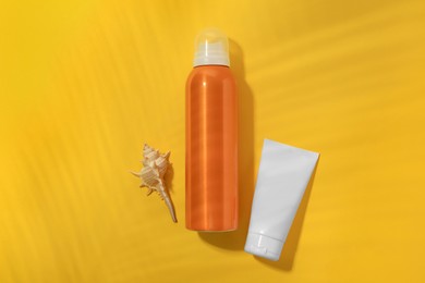 Sunscreens and seashell on yellow background, flat lay. Sun protection care