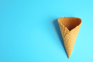 Empty wafer ice cream cone on blue background, top view. Space for text