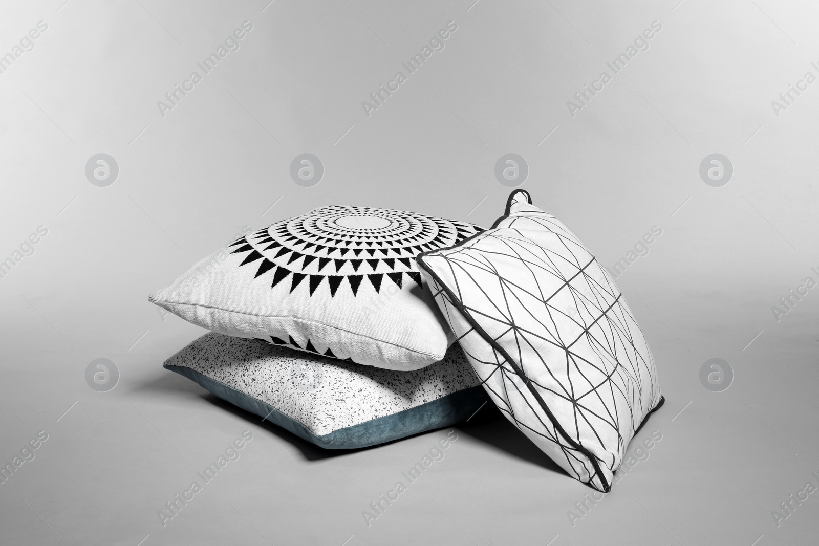 Photo of Pile of stylish decorative pillows on light background