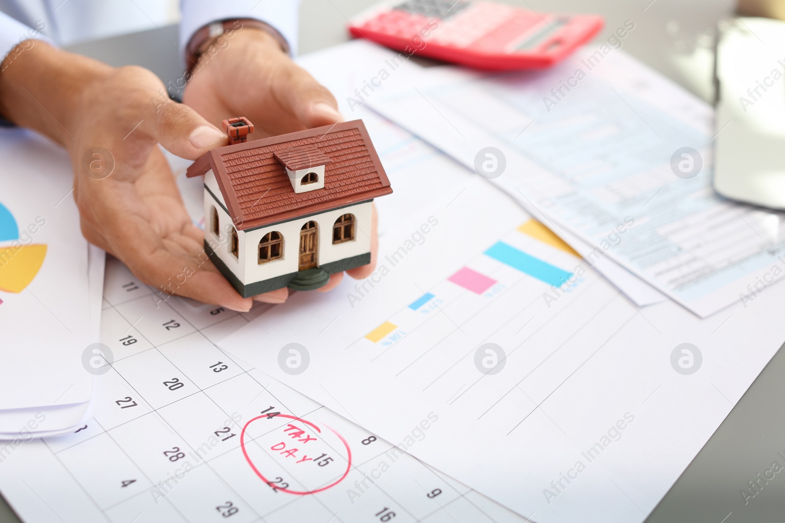 Photo of Man holding house model at table, closeup. Property tax