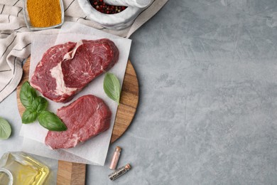 Photo of Flat lay composition with cut fresh beef meat on grey table. Space for text