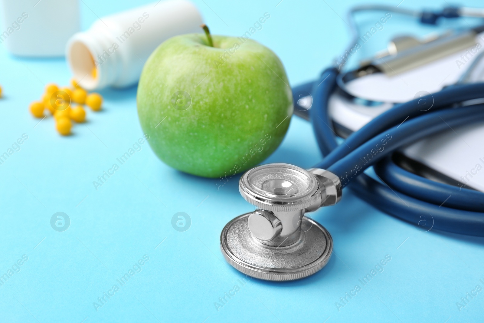 Photo of Stethoscope and apple on color background. Medical equipment