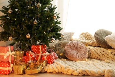 Beautiful Christmas tree and gift boxes in light room. Interior design