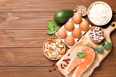 Photo of Set of natural food high in protein and space for text on wooden background, top view