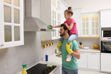 Photo of Spring cleaning. Father and daughter tidying up in kitchen together