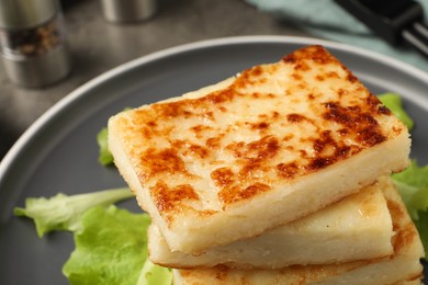 Photo of Delicious turnip cake with lettuce salad on grey plate, closeup