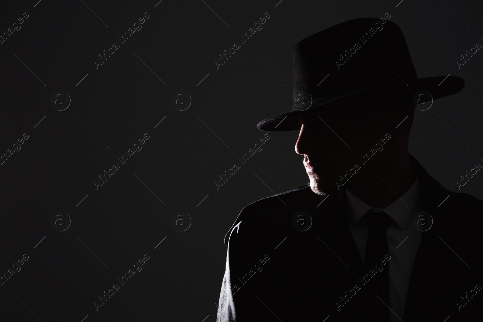 Photo of Old fashioned detective in hat on dark background. Space for text