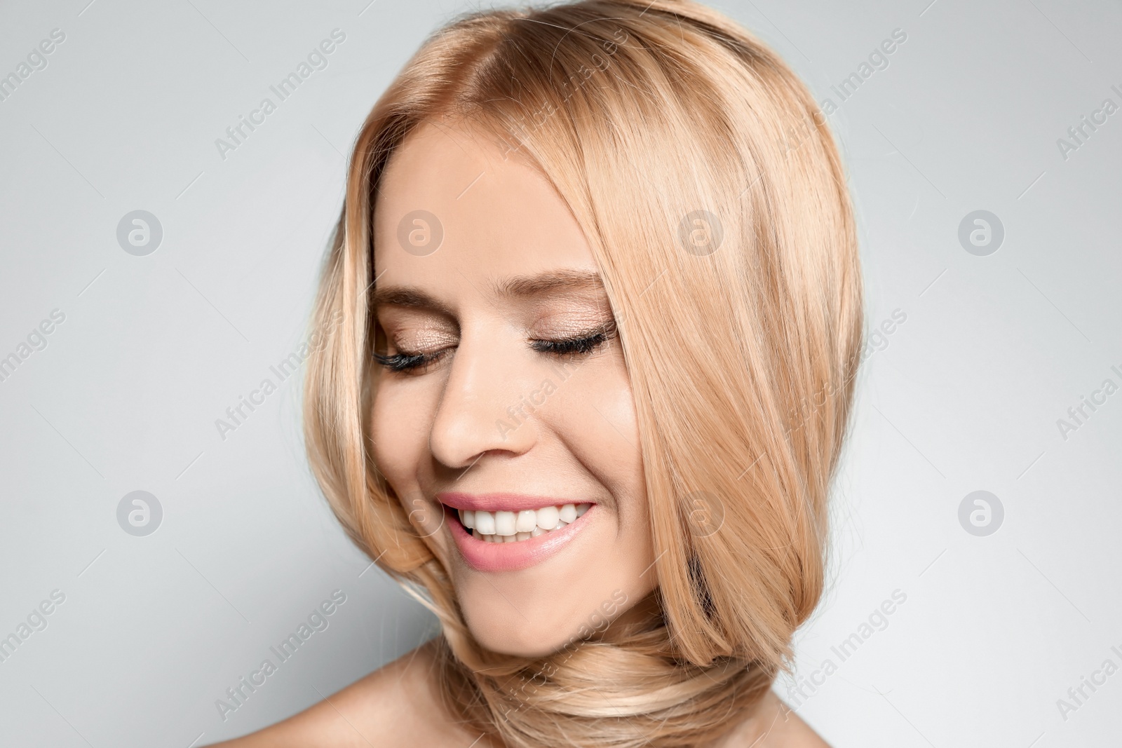 Photo of Beautiful woman with healthy long blonde hair on light background