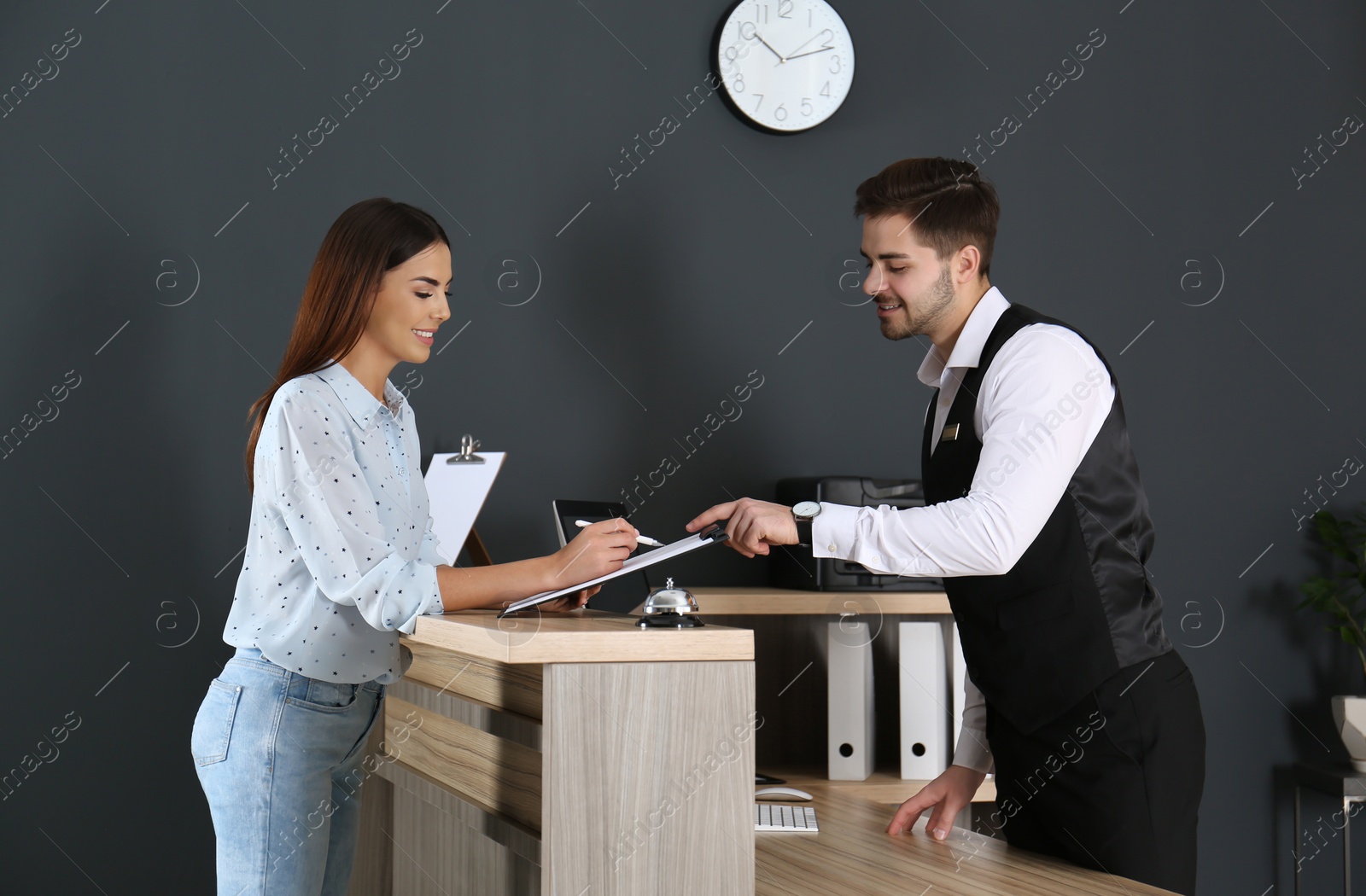 Photo of Receptionist registering client at desk in lobby