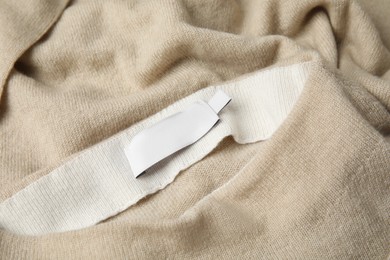 Photo of Warm beige cashmere sweater with clothing label, closeup