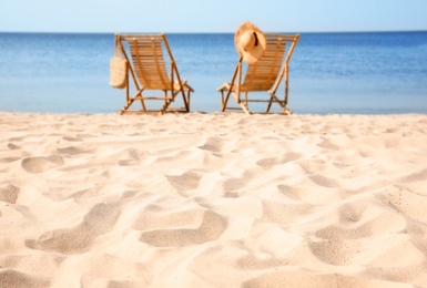 Photo of Wooden deck chairs on sandy beach near sea