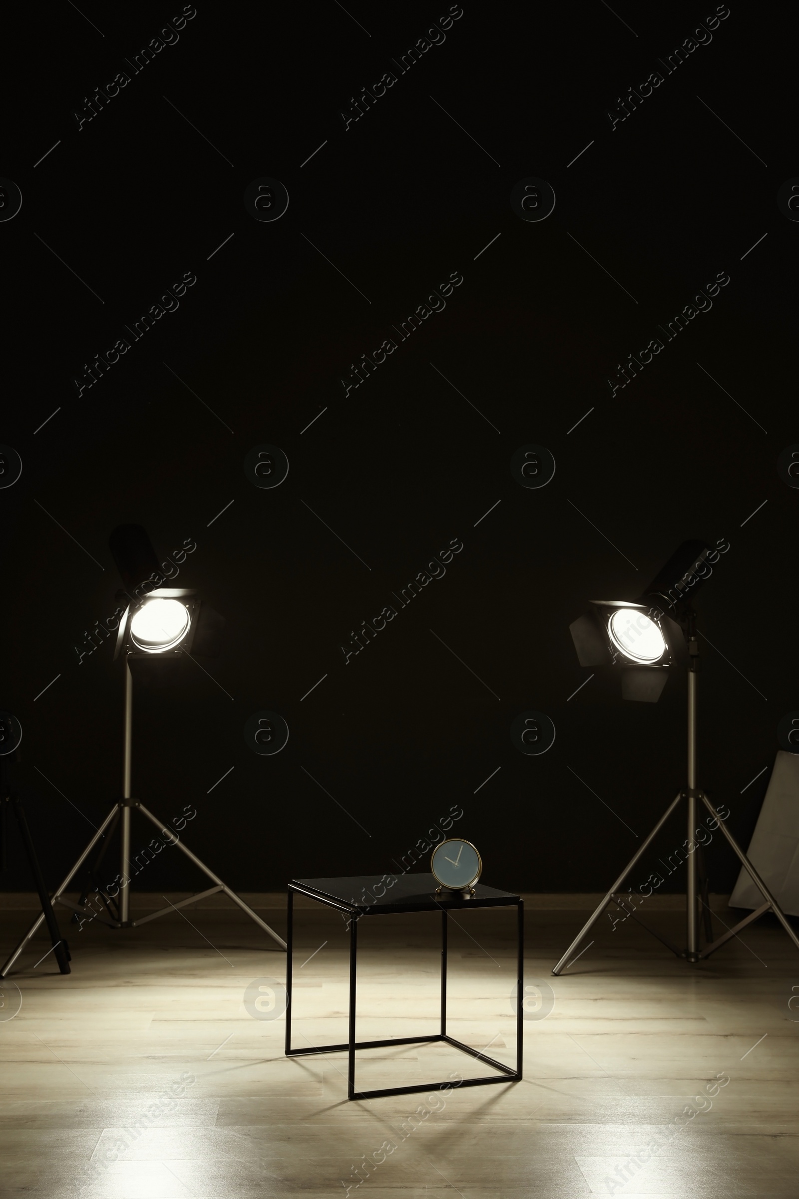 Photo of Interior of modern photo studio with table, clock and professional equipment