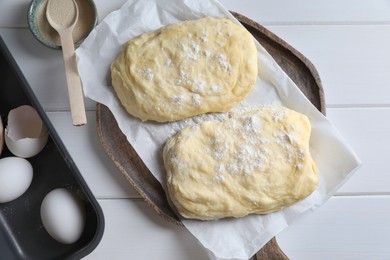 Dough, eggs and flour on white wooden table, flat lay. Cooking ciabatta