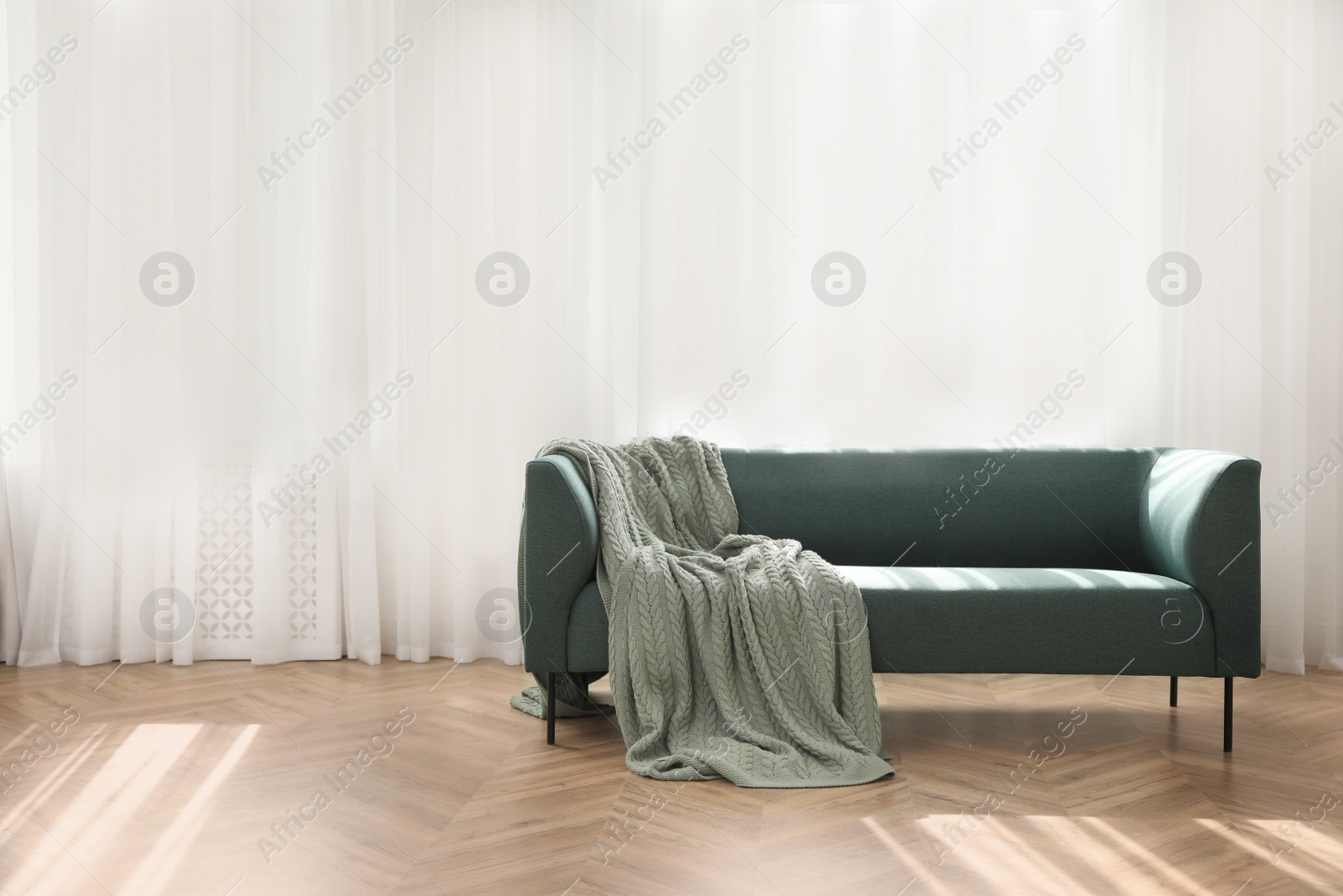 Photo of Stylish living room interior with comfortable green sofa and blanket near window. Space for text