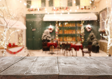 Image of Empty wooden surface and blurred view of outdoor cafe in winter. Christmas holiday