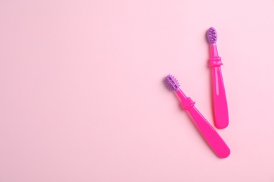 Manual toothbrushes for children on color background, top view with space for text