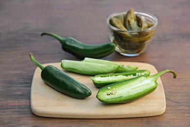 Fresh and pickled green jalapeno peppers on wooden table, closeup