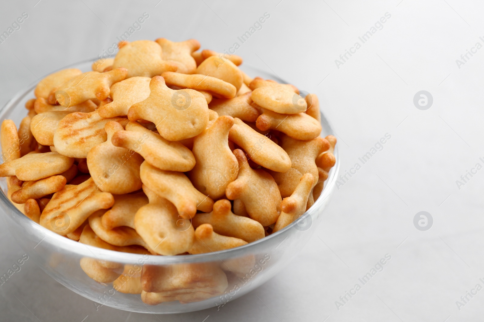 Photo of Delicious goldfish crackers in bowl on grey table, closeup
