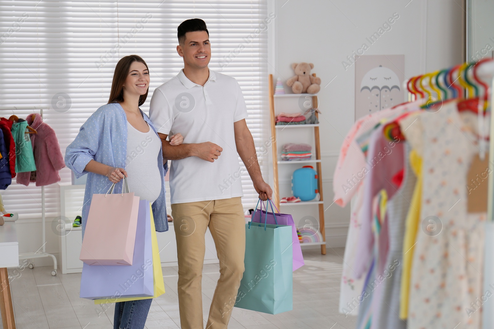 Photo of Happy pregnant woman and her husband with shopping bags in store