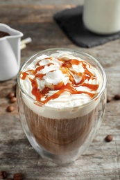 Glass of coffee with caramel topping on wooden background