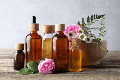 Aromatherapy. Different essential oils and flowers on wooden table