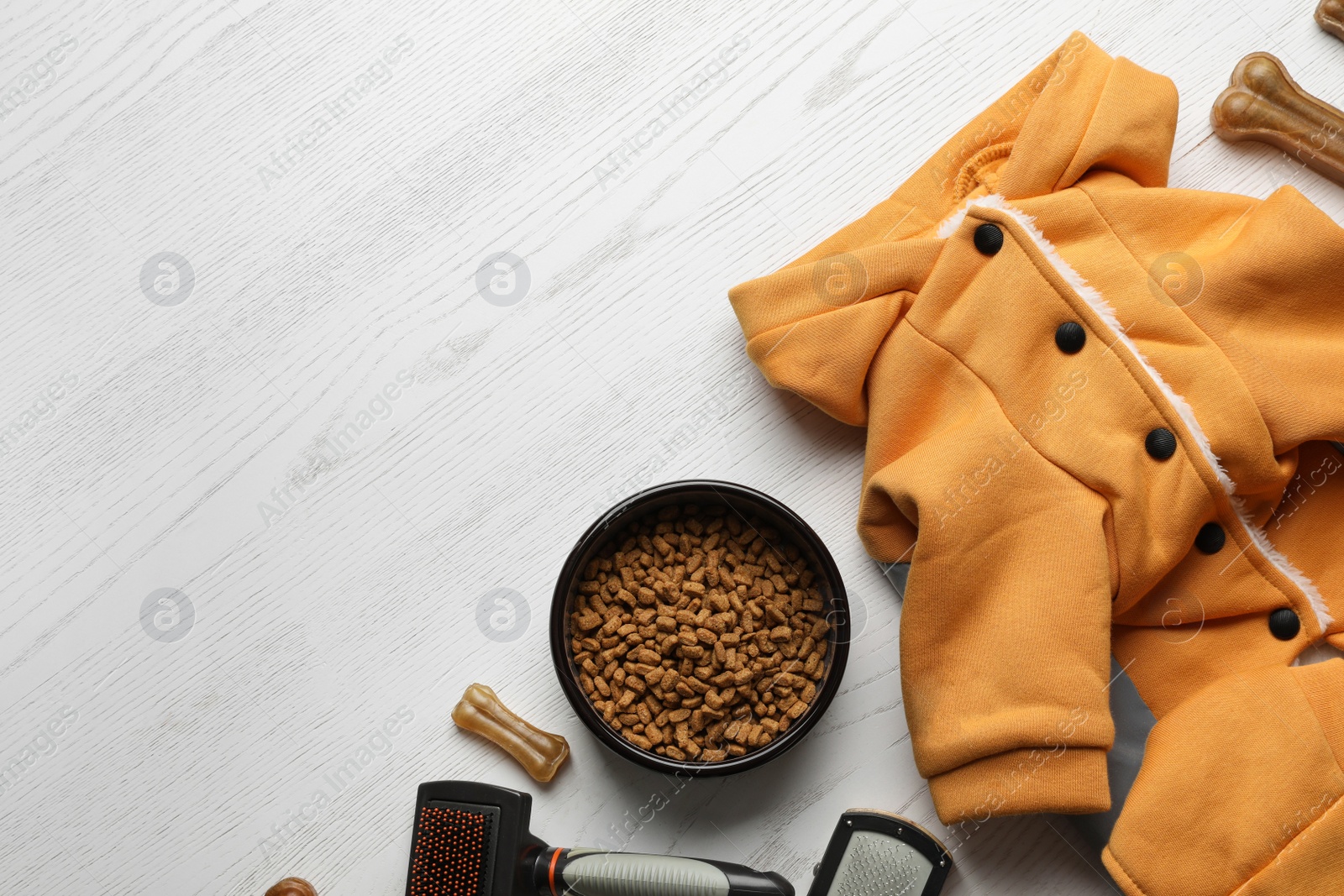 Photo of Flat lay composition with dog clothes, food and accessories on white wooden table. Space for text