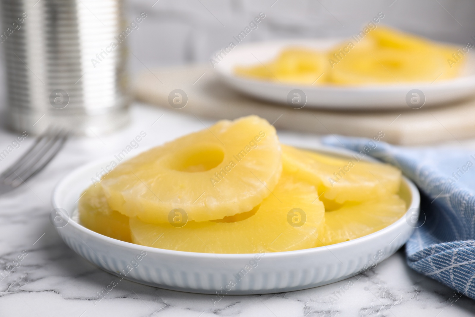 Photo of Tasty canned pineapple slices on white marble table, closeup