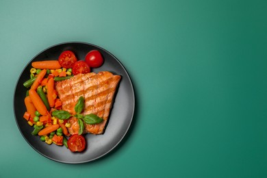 Tasty grilled salmon with mixed vegetables on green background, top view. Space for text