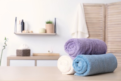 Rolled tidy towels on table in bathroom. Space for text