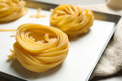 Raw tagliatelle pasta in baking pan, closeup view
