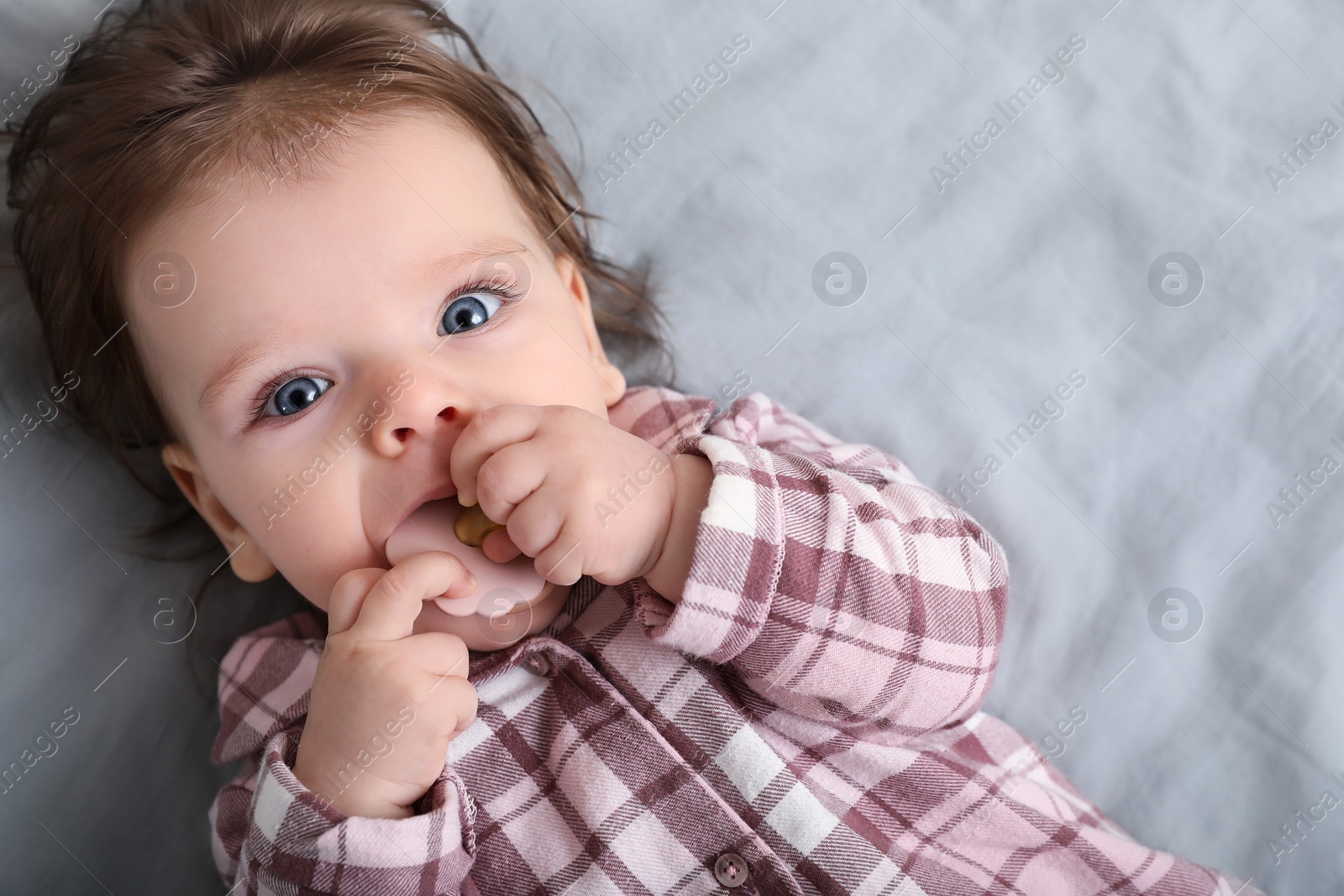 Photo of Cute little baby with pacifier on bed, top view