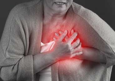 Mature woman having heart attack on dark background