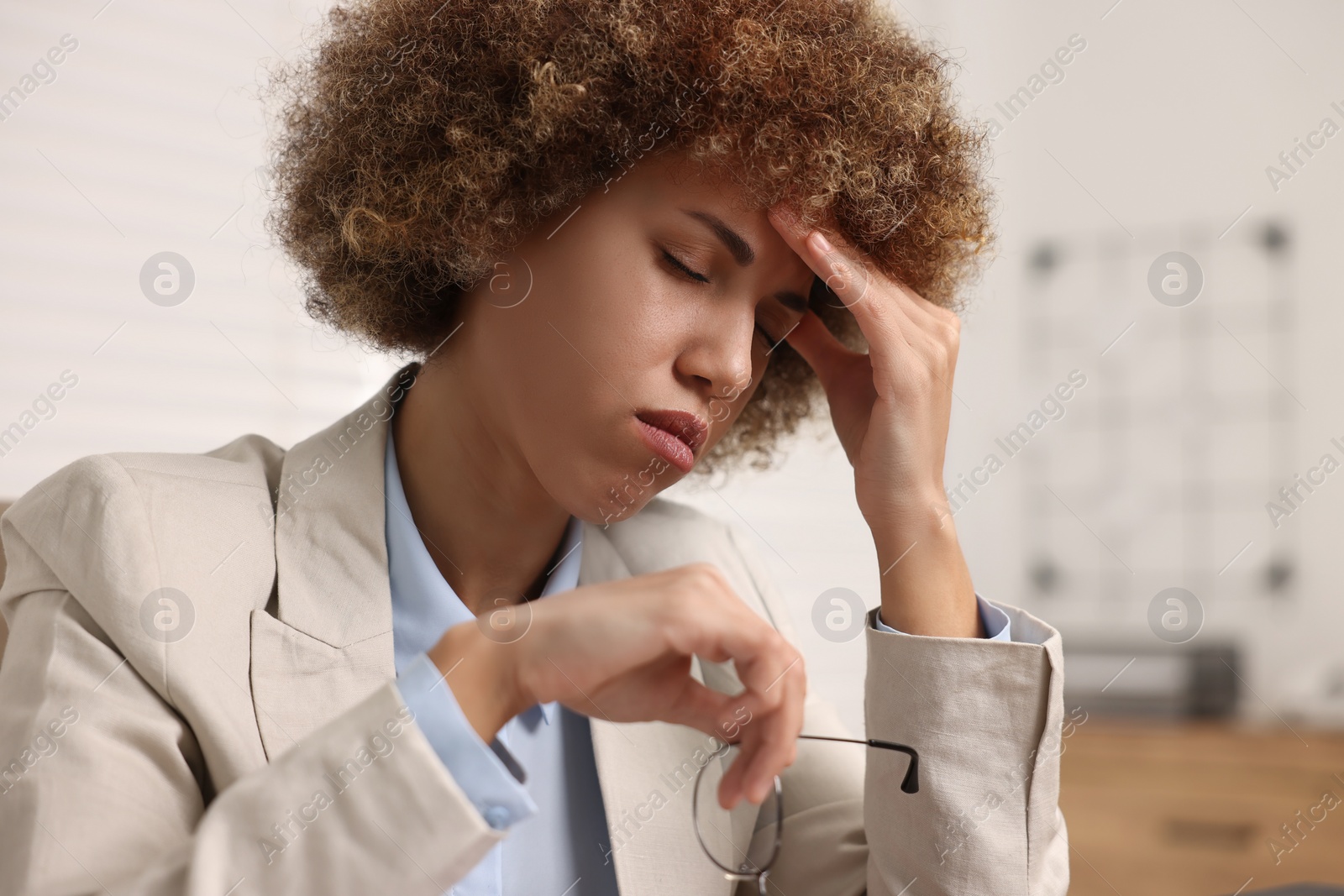 Photo of Young woman suffering from headache in office