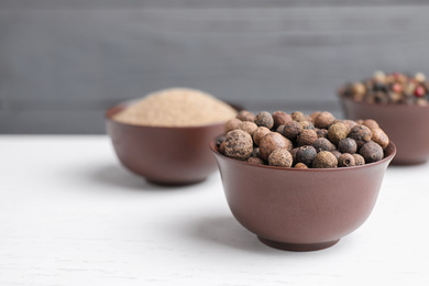 Photo of Peppercorns on white wooden table, closeup. Space for text