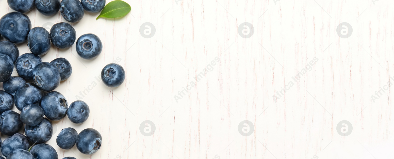 Image of Tasty fresh blueberries on white wooden background, top view with space for text. Banner design