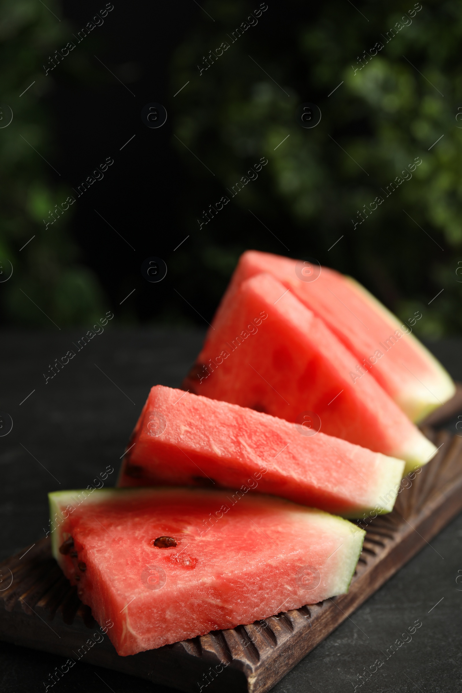 Photo of Cut ripe watermelon on black table, closeup