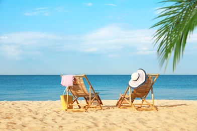 Empty wooden sunbeds and beach accessories on sandy shore