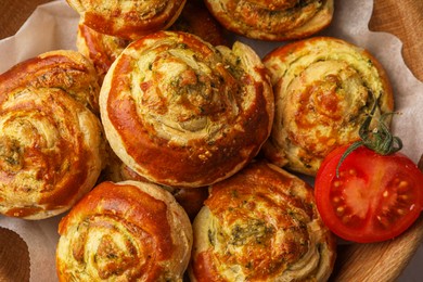 Photo of Fresh delicious puff pastry with tasty filling and tomato in wooden bowl, top view