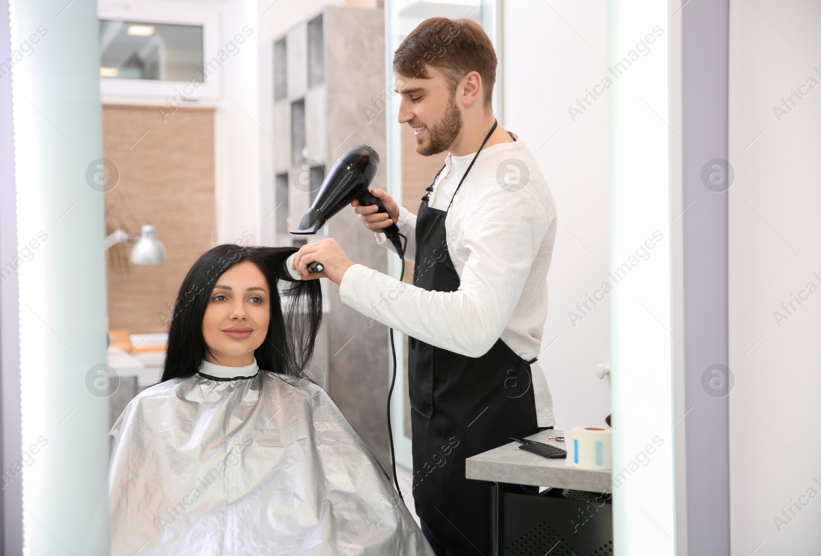 Photo of Professional male hairdresser working with client in salon