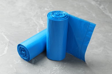 Photo of Rolls of light blue garbage bags on grey marble table